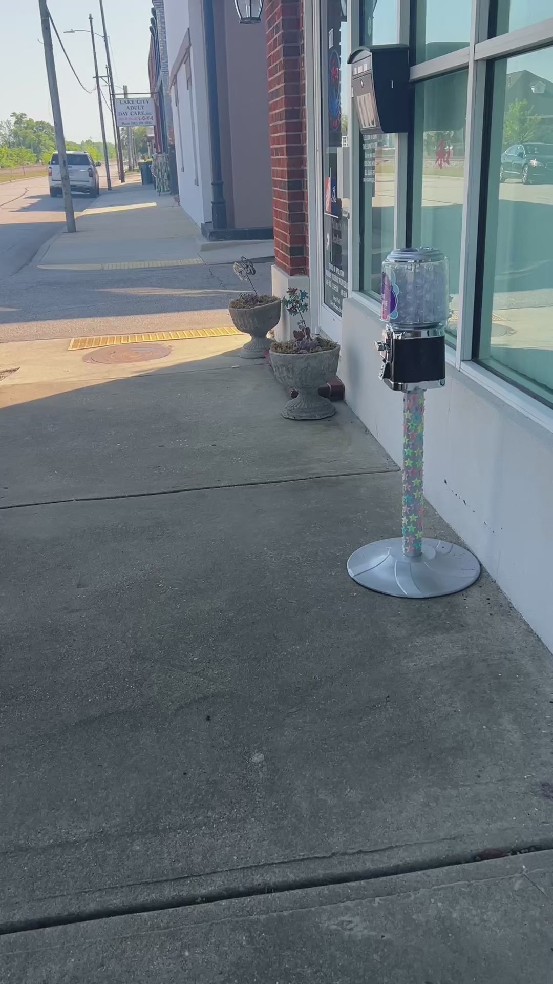 A gumball machine filled with story fortune capsules on a sidewalk. As the camera approaches, we see the dial turned, a capsule come out, and a one-line fortune story for the participant revealed. 